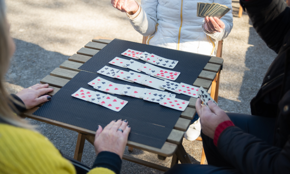 Player enjoying a game of solitaire on an outdoor folding table, with sunlight streaming in